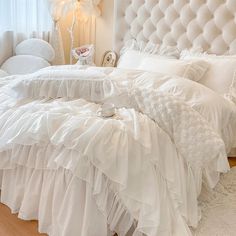 a white bed with ruffled bedspread and pillows