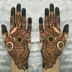 two hands with henna designs on them, one is showing the intricate design and the other has an intricate pattern