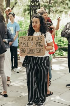 a woman holding a sign that says it's just one plastic straw and cotton people