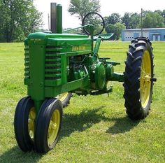 a green tractor parked on top of a lush green field