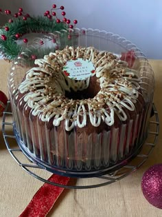 a cake with frosting and nuts is on a wire rack next to christmas decorations