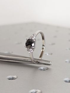 a diamond ring sitting on top of a piece of metal with tiny dots around it