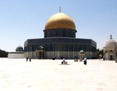 some people are standing in front of a building with a golden dome on the top