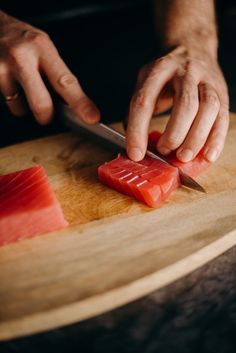 a person is cutting up some fish on a wooden board