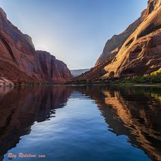 the sun shines brightly on the canyon walls and reflecting in the still water surface