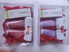 two clear boxes with red ribbon wrapped in white towels and purple shampoos on them