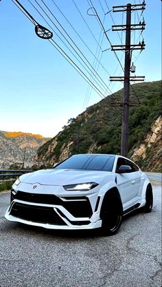 a white sports car parked on the side of a road with power lines in the background