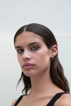 a woman with blue eyes and long dark hair wearing black top looking at the camera