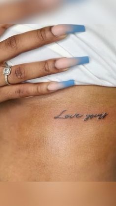 a woman's lower back with the word love you tattooed on her left side