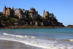 a person is swimming in the ocean near an old castle