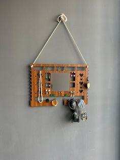 a wall mounted wooden jewelry organizer hanging on a gray wall