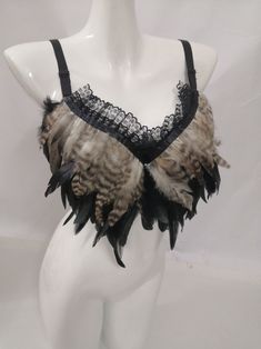 a white mannequin with black lace and feathers on it's neckline