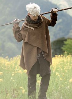 an old woman with white hair holding a stick in her hand while standing in a field