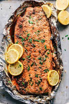 baked salmon on foil with lemons and parsley sprinkled around the edges