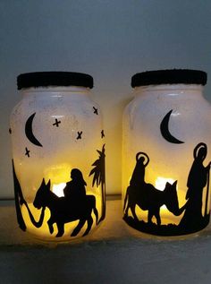 two mason jars with nativity images on them, one is lit up and the other has