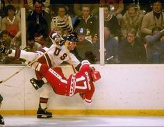 two hockey players in red and white uniforms on the ice with their legs stretched out