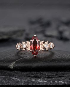 a close up view of a red and white diamond ring on top of a rock