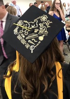 a woman in a graduation cap with writing on the back of her hat and yellow tassel