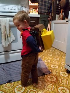 a little boy standing in front of an oven with a bag on it's back