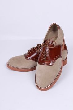 Casual two-tone 1950s-style oxford/saddle shoes with brogue pattern. These two-tone, 1950s-inspired, casual everyday oxfords feature an almond-shaped toe cap. The shoe is made of suede and features cognac brown full-grain leather with a brogue pattern on the backstay and around the vamp. The outsole is crafted from lightweight rubber with white stitching on the welt. These shoes were initially men's shoes. But here, it is also made for women. The shoes have a casual, sporty, and authentic 50s lo Retro Almond Toe Oxfords For Workwear, Retro Oxfords With Brogue Detailing And Round Toe, Retro Brogue Oxfords With Round Toe, Brown Oxfords With Brogue Detailing For Derby, Retro Oxfords With Brogue Detailing For Work, Retro Brogue Oxfords For Work, Brown Brogue Oxfords For Derby, Classic Wingtip Oxfords With Contrast Sole, Brown Oxfords With Brogue Detailing For Semi-formal Occasions