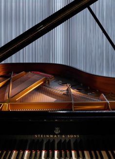 a grand piano sitting in front of a curtained wall with the words steinway & sons on it