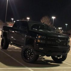 a black truck parked in a parking lot at night