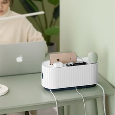 a woman sitting at a desk with an apple laptop and headphones in front of her