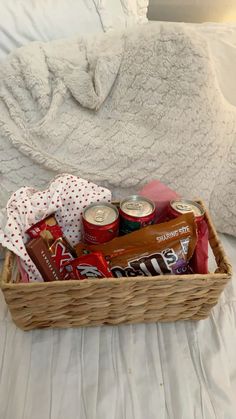 a basket filled with snacks and drinks on top of a bed next to a blanket