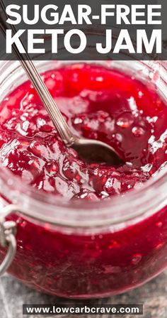 a glass jar filled with keto jam on top of a table next to a spoon