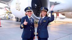 two women in air force uniforms standing next to an airplane on the tarmac with their thumbs up