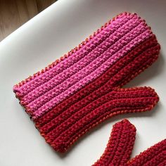 the knitted mitts are laying next to each other on a white table top