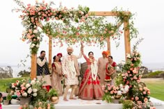 a group of people standing next to each other in front of a flower covered arch