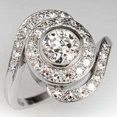 This wonderful circa 1950s ring features a swirl design and is centered with one (1), bezel set, old European cut diamond and is bordered with a halo of fifteen (15), bead set, round single cut diamonds. The by-pass style shank is accented with sixteen (16), bead set, round single cut diamonds. The ring measures 17.2mm at the top, rises 6.6mm above the finger, tapering to 1.7mm wide and 1.4mm thick at the base of the shank. This ring is currently a size 7.25. Vintage Diamond Ring With Halo Design, Vintage Halo Diamond Ring, 1950s Engagement Ring, 1950s Ring, Unique Gold Jewelry Designs, Diamond Girl, High Jewellery, Swirl Ring, Diamond Jewel