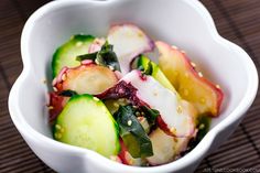 a white bowl filled with cucumbers and other vegetables on top of a table