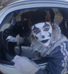 a person with painted face sitting in the back seat of a car