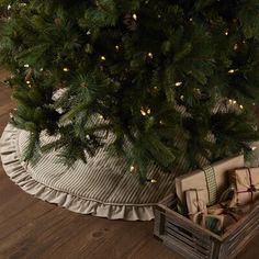 a small christmas tree in a wooden crate with presents under it on a wood floor