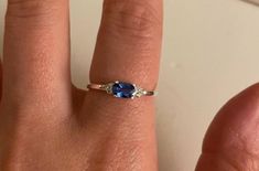 a woman's hand with a ring on it and a blue stone in the middle