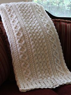 a white crocheted blanket sitting on top of a couch next to a window