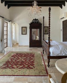 a large bed sitting in the middle of a bedroom next to a chandelier