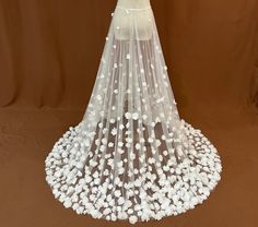 a wedding veil with white flowers on the bottom is shown in front of a brown background