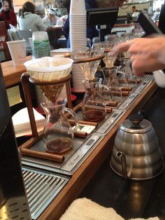 a person pouring coffee into glasses on a counter