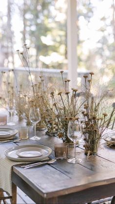 the table is set with place settings and flowers in glass vases on each side