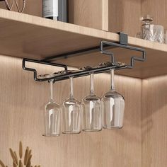 three wine glasses hanging from a shelf in a kitchen