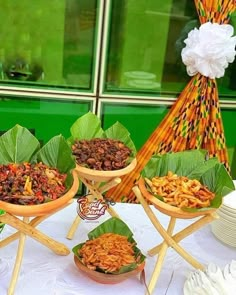 a table topped with bowls filled with food next to plates and utensils on top of a white table cloth