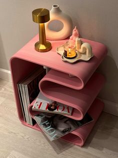 a pink shelf with magazines and candles on it