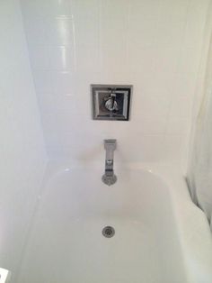 a white bath tub sitting under a bathroom faucet next to a shower head