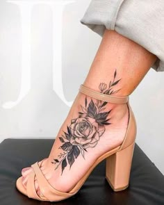 a woman's foot with a rose tattoo on the side of her leg and ankle