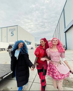 three women dressed up in costumes walking down the street with one woman holding her hand