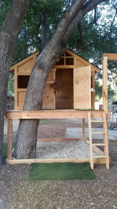 a tree house built into the side of a tree in front of a large tree