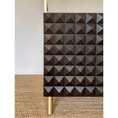 a black and gold table lamp sitting on top of a carpeted floor next to a wall